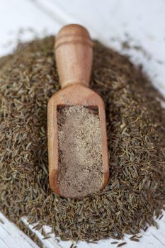 Grounded cumin seeds in a wooden spoon over the seeds