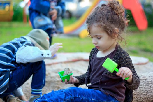 Little kid girl playing with the sand on the playground