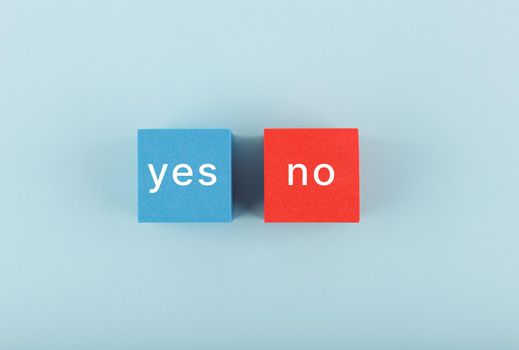 Yes and no written on blue and red cubes on bright blue. Concept of positive and negative answer, checklist, questionnaire