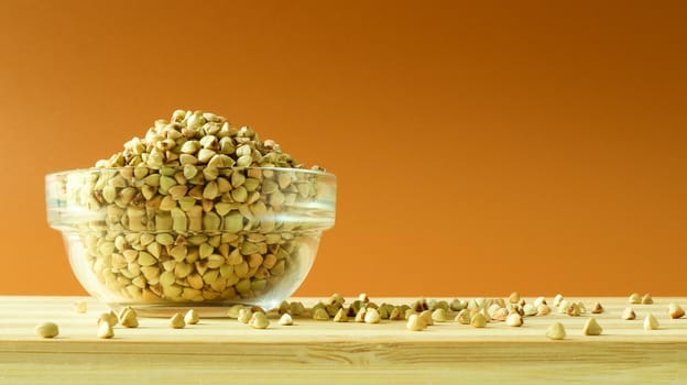 Green buckwheat in a glass transparent bowl on a brown background. healthy groats. Organic raw non-fried vegetarian food. The concept of a healthy and balanced diet. Diet Food. Copy Space.