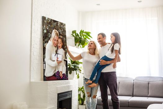 Smiling family holding photo canvas.