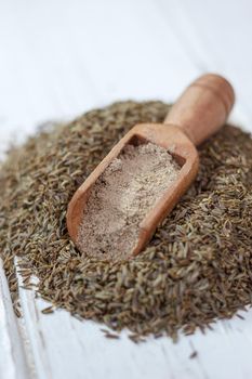 Grounded cumin seeds in a wooden spoon over the seeds