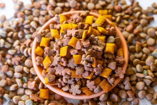 Top view of natural pet food in a clay bowl on white table.