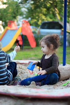 Little kid girl playing with the sand on the playground