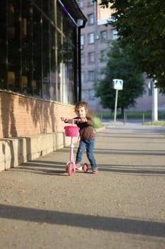 Yong kid girl ride on street on child scooter