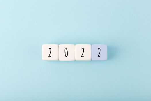 2022 numbers written on white toy blocks as a calendar against bright blue background with copy space. Minimal elegant business style concept of upcoming 2022 year