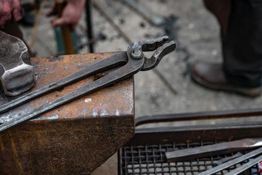 Metal tongs over the anvil - blacksmith equipment.