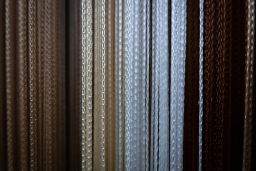 Textile strings and ropes hangs in a fabric shop. Abstract background