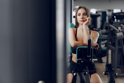 Young beautiful woman training her arms in a gym apparatus in a gym