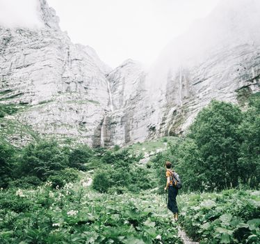 Explorer young man with backpack going to Pshehsky waterfalls in Caucasus mountains, Russia.