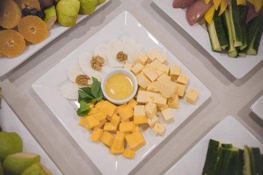 Cheese snack cubes stand on a table in a square plate along with other dishes. Close up