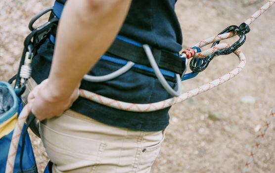 Climber in safety harness belaying with rope and figure eight outdoor, close-up.