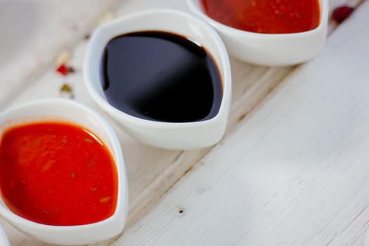 Different dips and sauces - red, white and black over white table, great image for your needs.