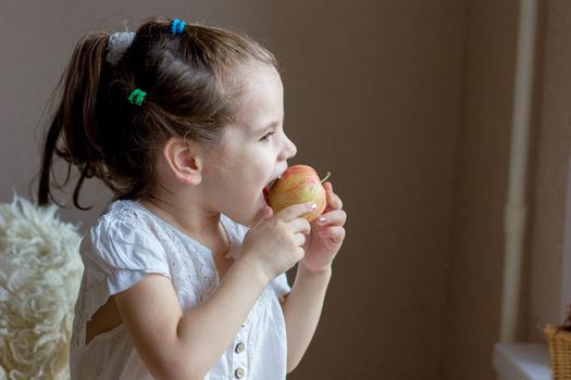 Funny little girl kid eats an apple.