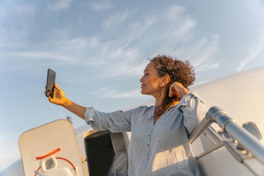 Side view of happy female passenger making selfie on smartphone before the flight. Trip concept