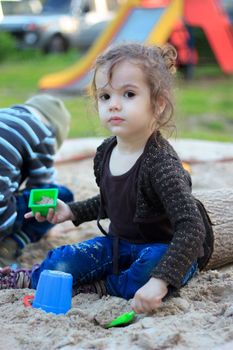 Little kid girl playing with the sand on the playground