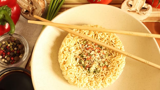 Instant noodles with king mushrooms, seasonings, soy sauce, peppers, green onions, tomatoes. Vegetable fast vegetarian soup. The process of cooking Asian food on the table. Vermicelli, spaghetti.