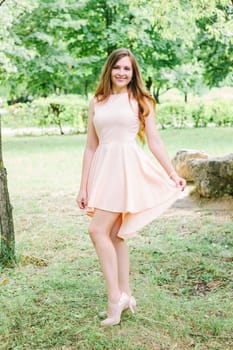 Beautiful young woman standing at a park and smiling