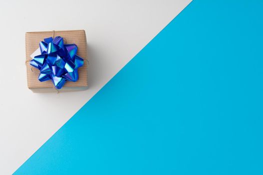 Top view of gift box with ribbon on blue background with copy space