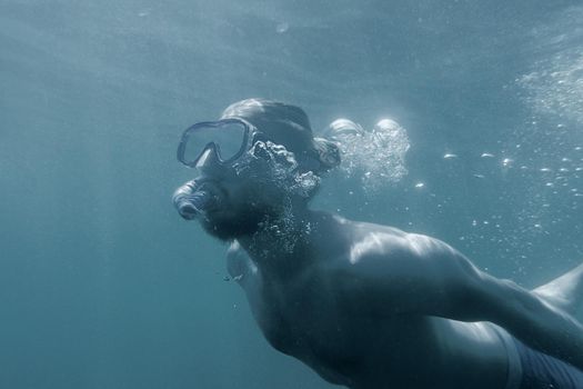 Sporty handsome young man snorkeling underwater.