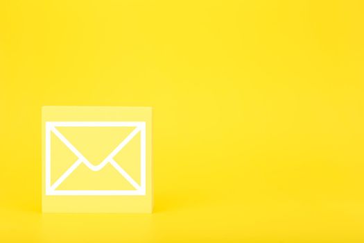 Email marketing, newsletter, promotion information and virtual communication concept. Envelope drawn on small toy cube against bright yellow background with copy space.