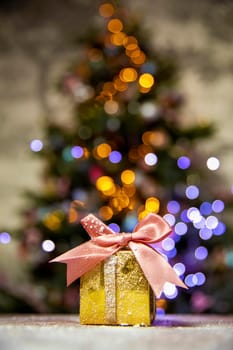 Gold Christmas gifts with pink bow, with Christmas tree bokeh lights background and copy space, Holiday, present xmas concept space for text