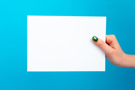 Woman hand holding blank card on blue background, close up.