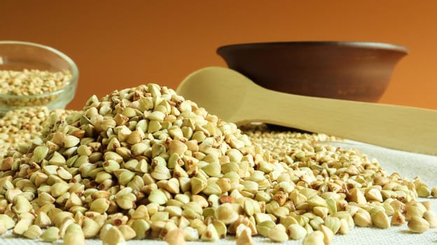 Raw green organic buckwheat in plates and lies in a scattered pile on a table in the kitchen. Diet food. Copy space. The concept of vegetarianism, balanced and healthy nutrition