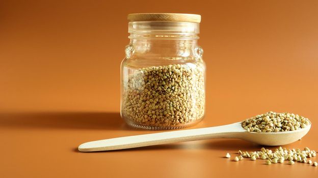 Green buckwheat sprouts in a glass jar with a wooden spoon. Raw vegan food concept. Organic food. The concept of diet, weight loss, healthy and proper nutrition. Copy space. Space for text