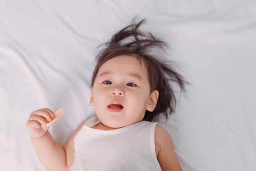 Little girl lies in bed eating potato chip