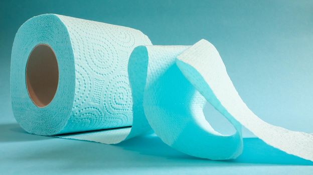 Blue roll of modern toilet paper on a blue background. A paper product on a cardboard sleeve, used for sanitary purposes from cellulose with cutouts for easy tearing. Embossed drawing.