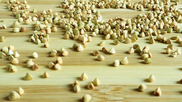 Green buckwheat seeds on a wooden background. Great food. healthy groats. Organic raw non-fried vegetarian food. The concept of a healthy, balanced and dietary diet. Copy space