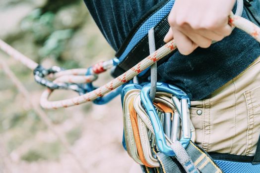 Sporty woman with climbing equipment belaying with rope and figure eight, close-up.
