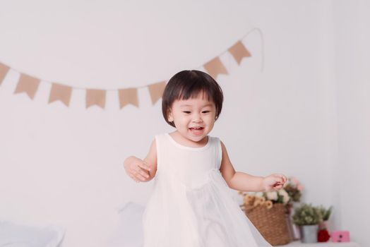 beautiful little girl stands on the bed