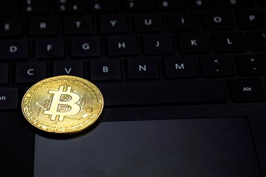 One golden bitcoin on dark black keyboard of computer, crypto currency,trading and technology concept with copy space pc