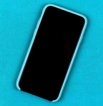 Black Mobile phone or smartphone in aqua blue case on a trendy aqua background with space for text.