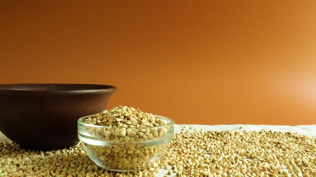Green buckwheat in a glass transparent bowl on a brown background. healthy groats. Organic raw non-fried vegetarian food. The concept of a healthy and balanced diet. Diet Food. Copy Space.
