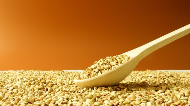 Buckwheat scattered background, raw green cereal in a wooden spoon. Healthy groats. Organic raw non-fried vegetarian food. The concept of a healthy and balanced diet. Diet product. healthy groats
