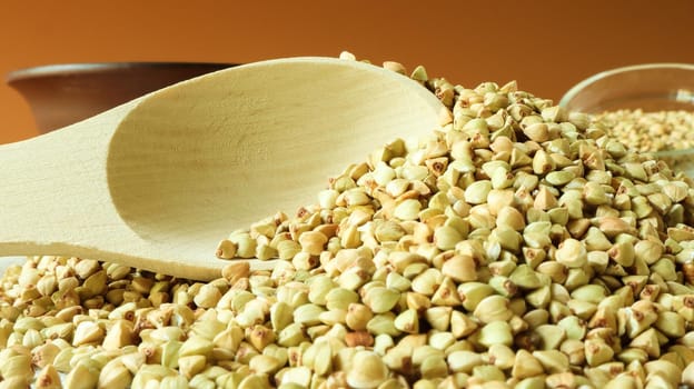 Buckwheat scattered background, raw green cereal in a wooden spoon. Healthy groats. Organic raw non-fried vegetarian food. The concept of a healthy and balanced diet. Diet product. healthy groats