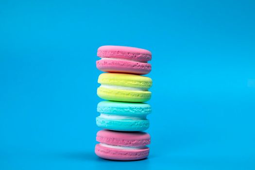 Pile of fresh baked colorful French macaroons on blue background , copy space banner. dessert,cookie,cake concept space for text