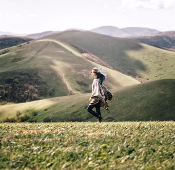 Boho style young woman walking in the mountains in windy weather.