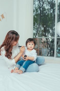 Beautiful young woman and little girl putting make up on