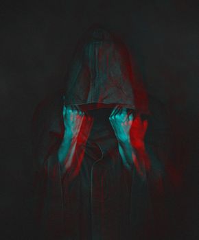 Unrecognizable human in black coat with a hood, face is not visible. Image with anaglyph effect.