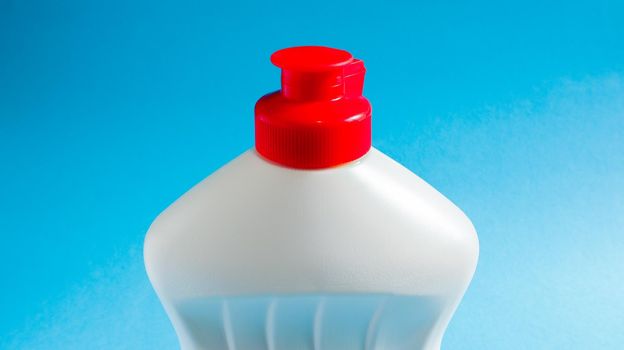 White plastic bottle with dishwashing detergent, bleach or fabric softener on a blue background. liquid washing powder. The concept of cleaning