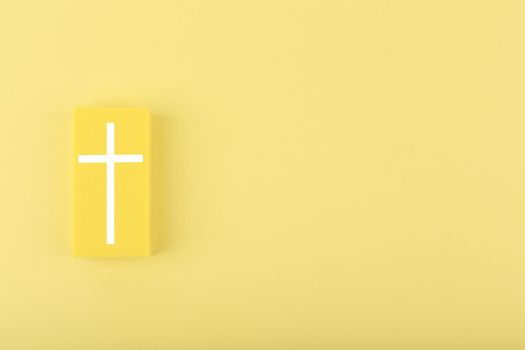 Modern religious minimal concept of hope with christian cross on bright yellow background with copy space. Biblical creative composition with white cross