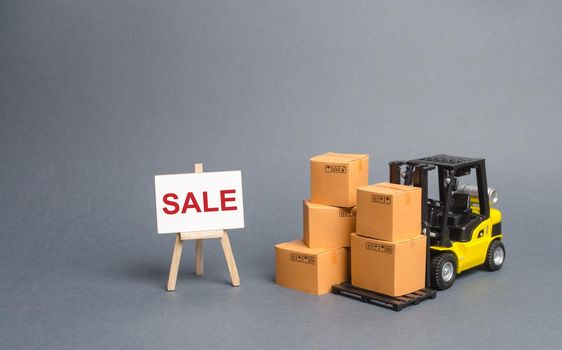 Yellow Forklift truck with cardboard boxes and stand with the word sale. sale of goods, big discounts on goods of the outgoing season. commodity exchange with other countries. Attracting buyers