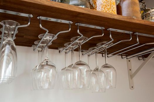 Wine glasses hanging in holder. organized inside cupboard. home interior storage close up