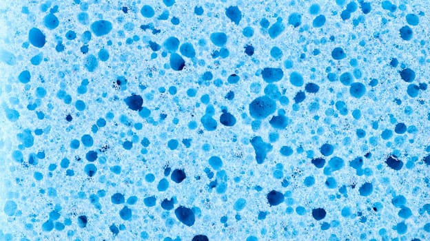 Background in the form of a porous structure in blue. Macro sponge. Close up blue sponge surface for textured background. copy space