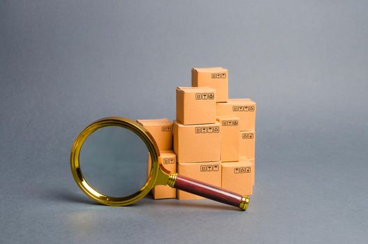 A pile of boxes and a magnifying glass. Concept search for goods and services. Tracking parcels. Quality control. Search for customers. Network monitoring system for the best supply of goods