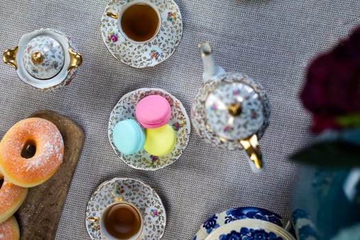 Traditional table with cup of tea and tea pot and colorful macaron lovely cozy table at home,Mother's Day tea setting with teapot, close up